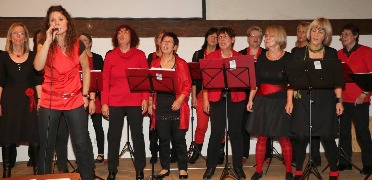 Der Frauenchor Li(e)dschatten in Rot und Schwarz auf der Bühne